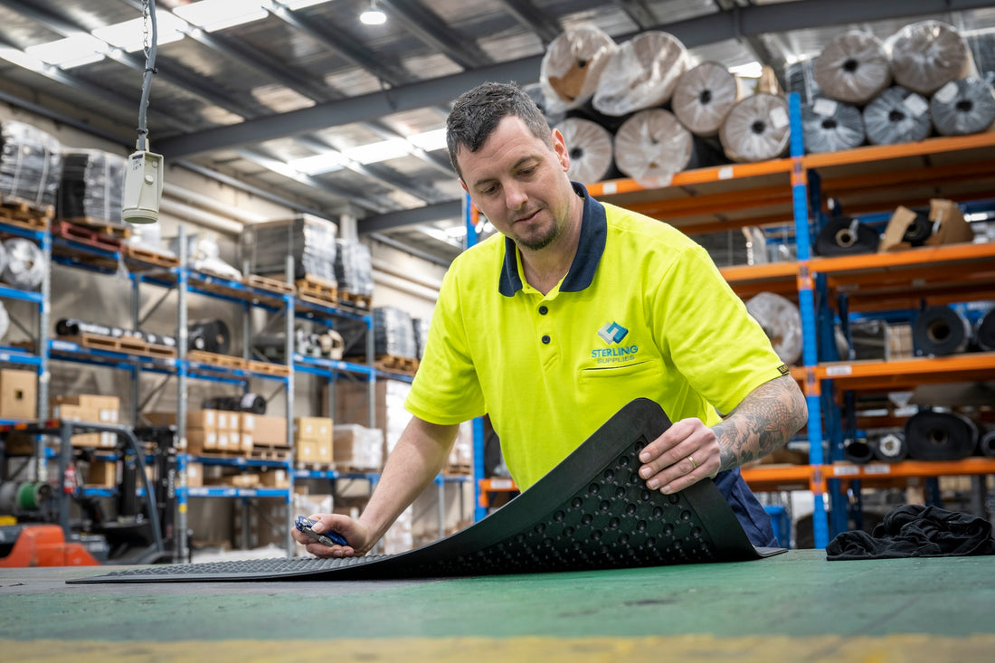 Person in a warehouse setting holding a large rubber mat